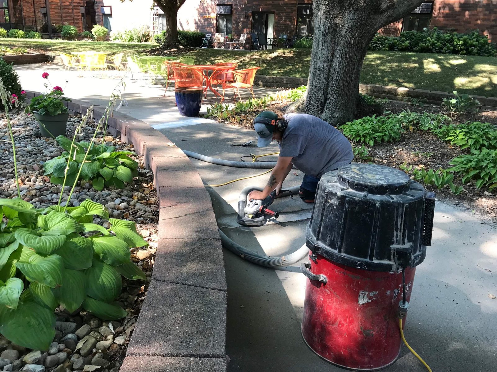 Kelly crew member grinding down a raised sidewalk joint with a dust-extraction vacuum attached